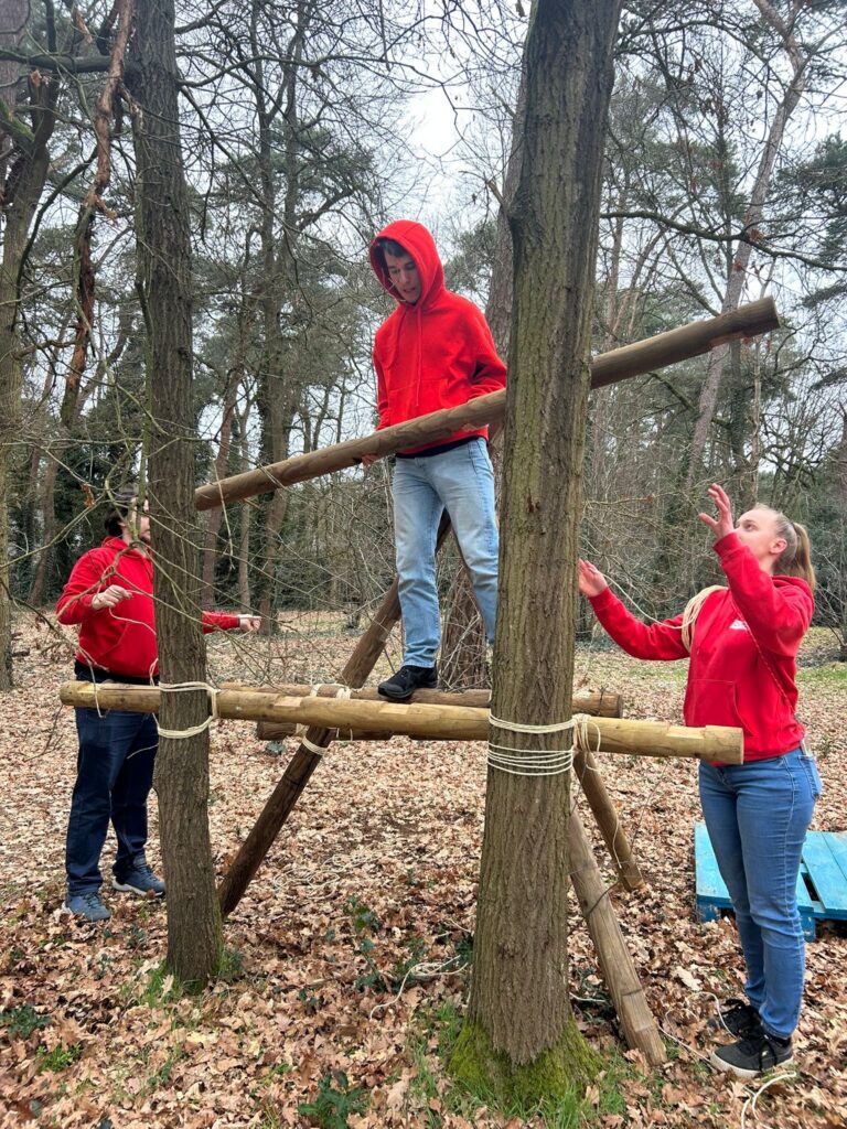 Animatoren werken samen om een kamp te bouwen tussen de bomen.